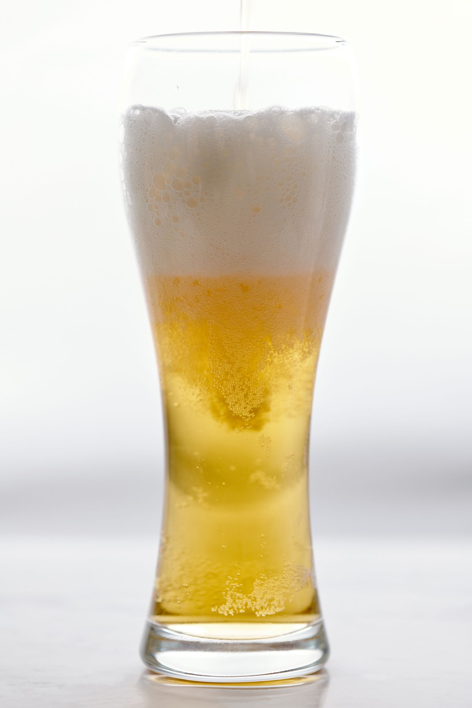 A pint of golden beer on a light background